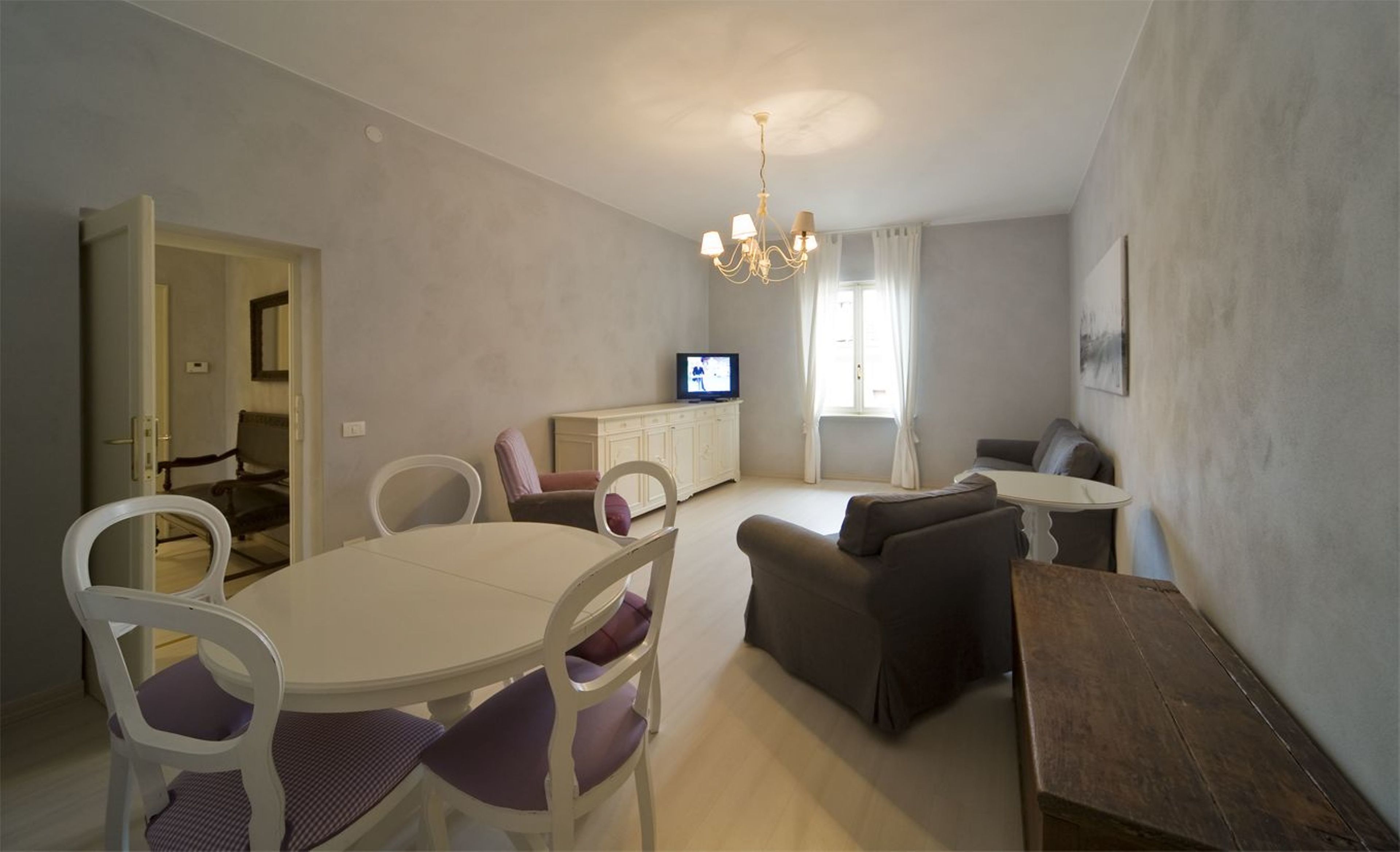 A compact living space with a dining area, a sofa, a TV, and a wooden table.