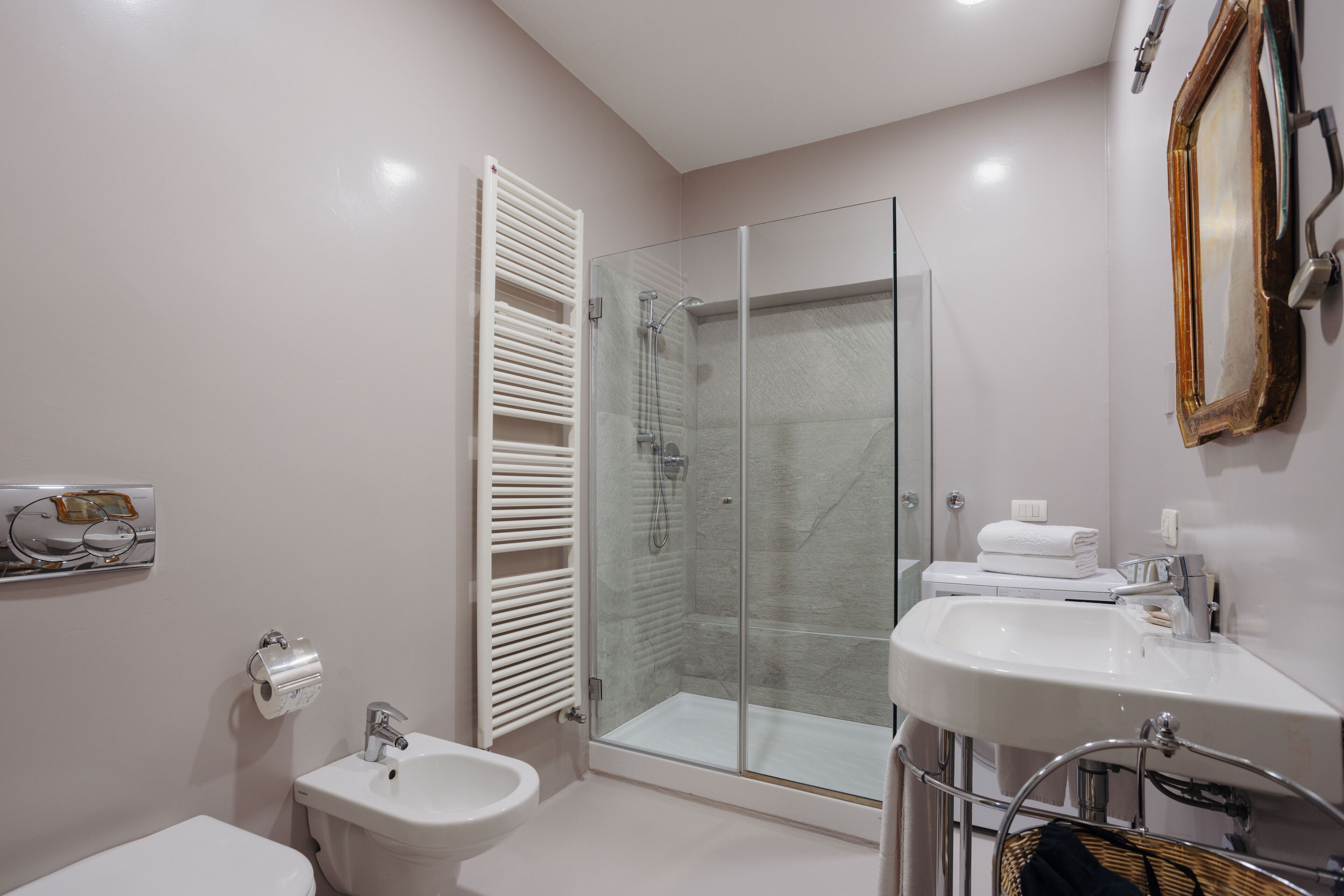 Ein modernes Badezimmer mit einer Glaskabine zur Dusche, einem weißen Waschbecken und einem Bidet.