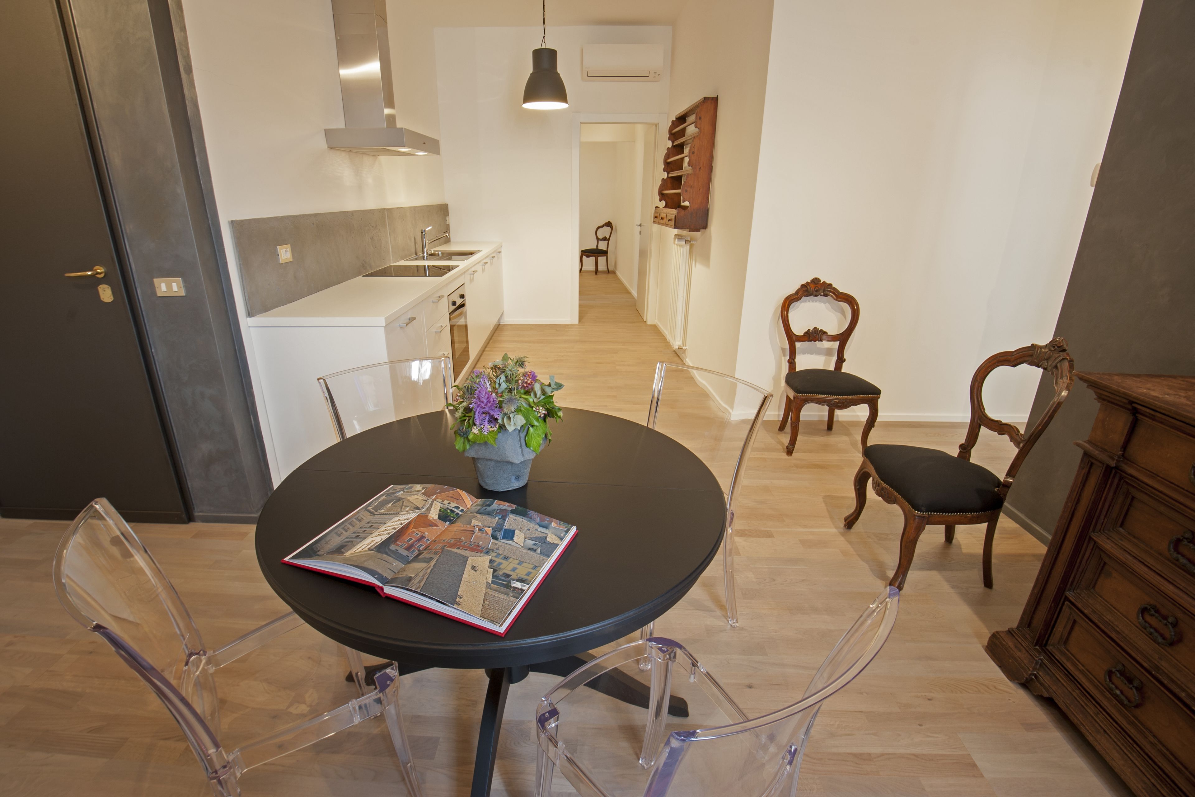A modern kitchen with white cabinets, a black countertop, and a wooden chair.