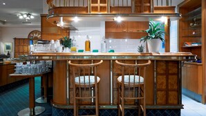 Cozinha moderna com ilha central, banquetas, armários de madeira e um vaso de planta.