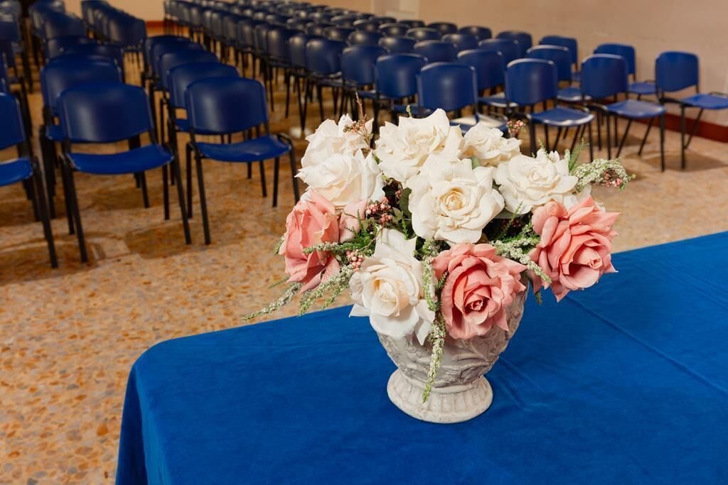 Une pièce où l’on trouve des rangées de chaises bleues et une table recouverte d’une nappe bleue.