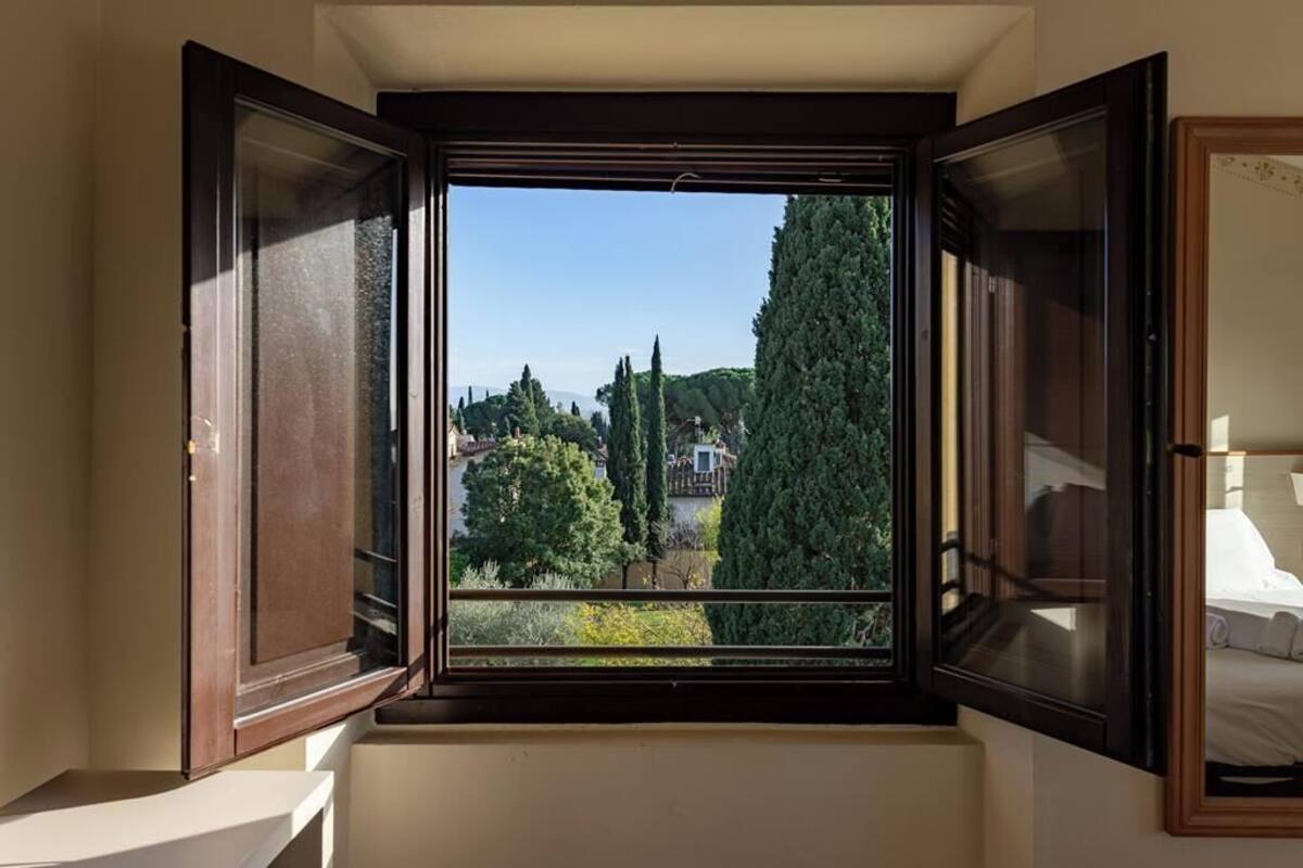 Une pièce dotée d’une grande fenêtre donnant sur un jardin et des bâtiments.