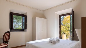 Een hotelkamer met een bed, een stoel, een kledingkast en een raam met uitzicht op bomen.