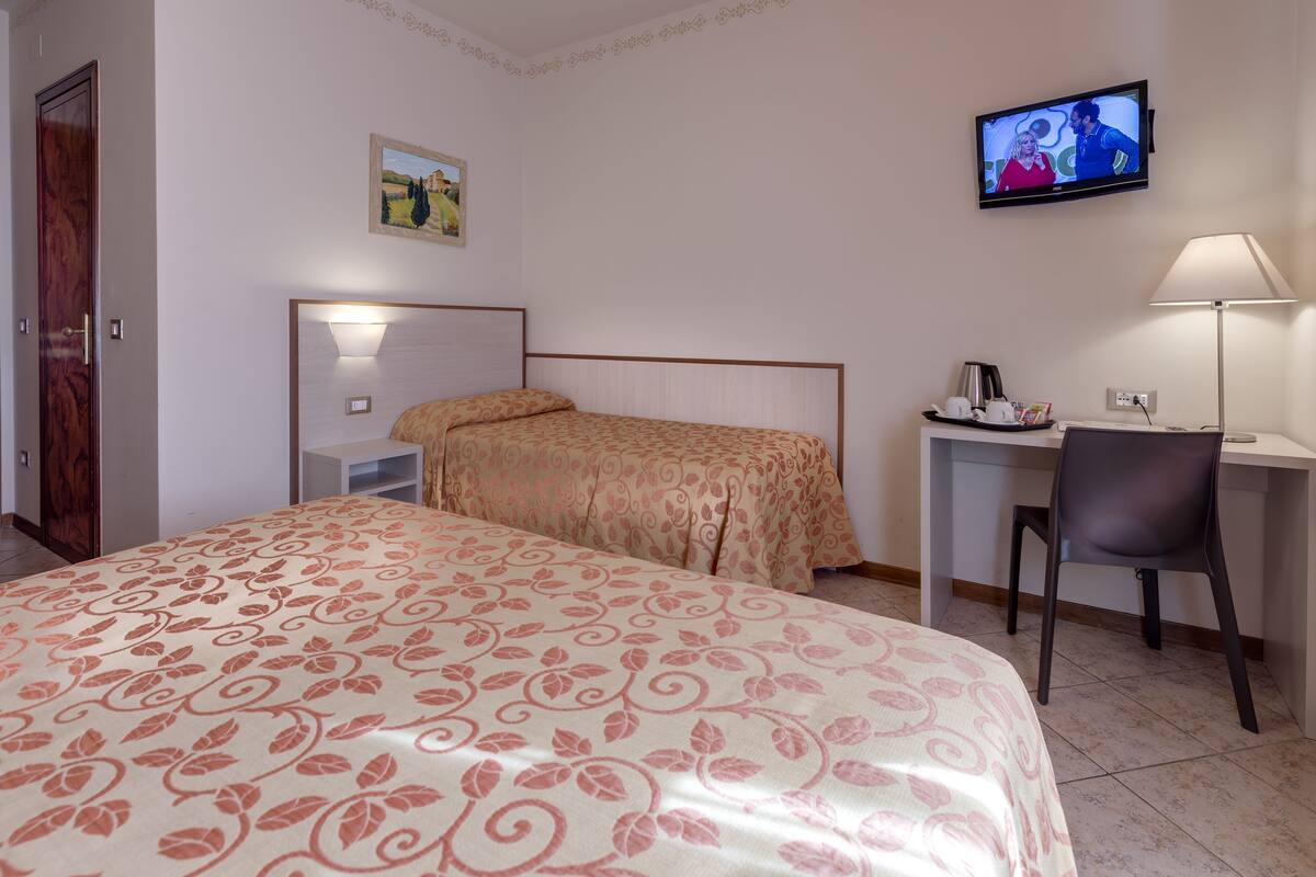 Une chambre d’hôtel avec un lit, un bureau, une chaise, une télévision et un tableau au mur.