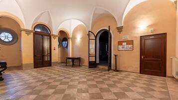 A spacious hallway with checkered flooring, arched ceilings, and multiple doors leading to different rooms.