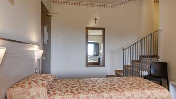 Ein Schlafzimmer mit einem Bett, einem Spiegel, einer Treppe und einem Kreuz an der Wand.