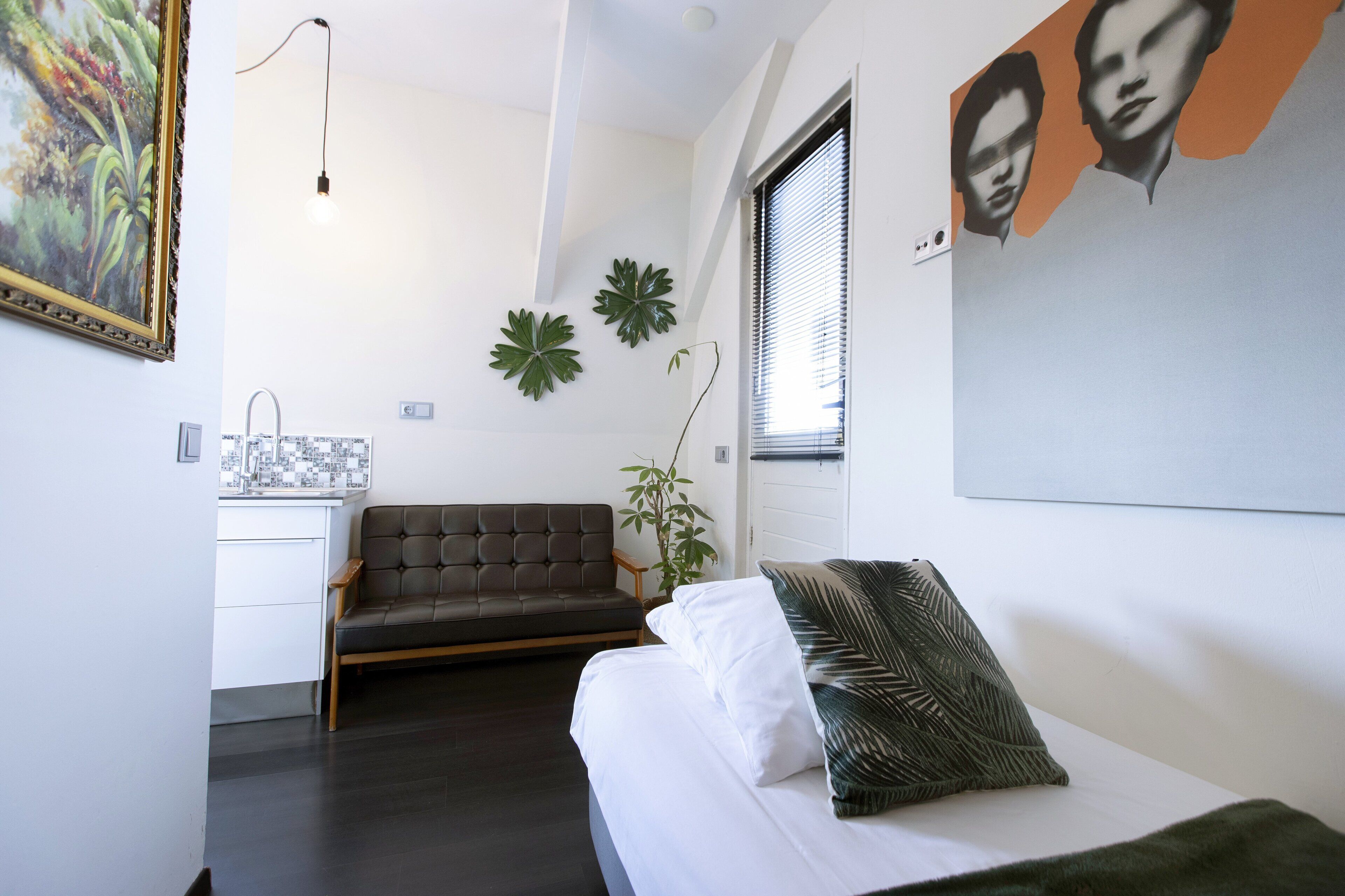 Un dormitorio moderno con cama, sofá, escritorio y ventana con persianas.