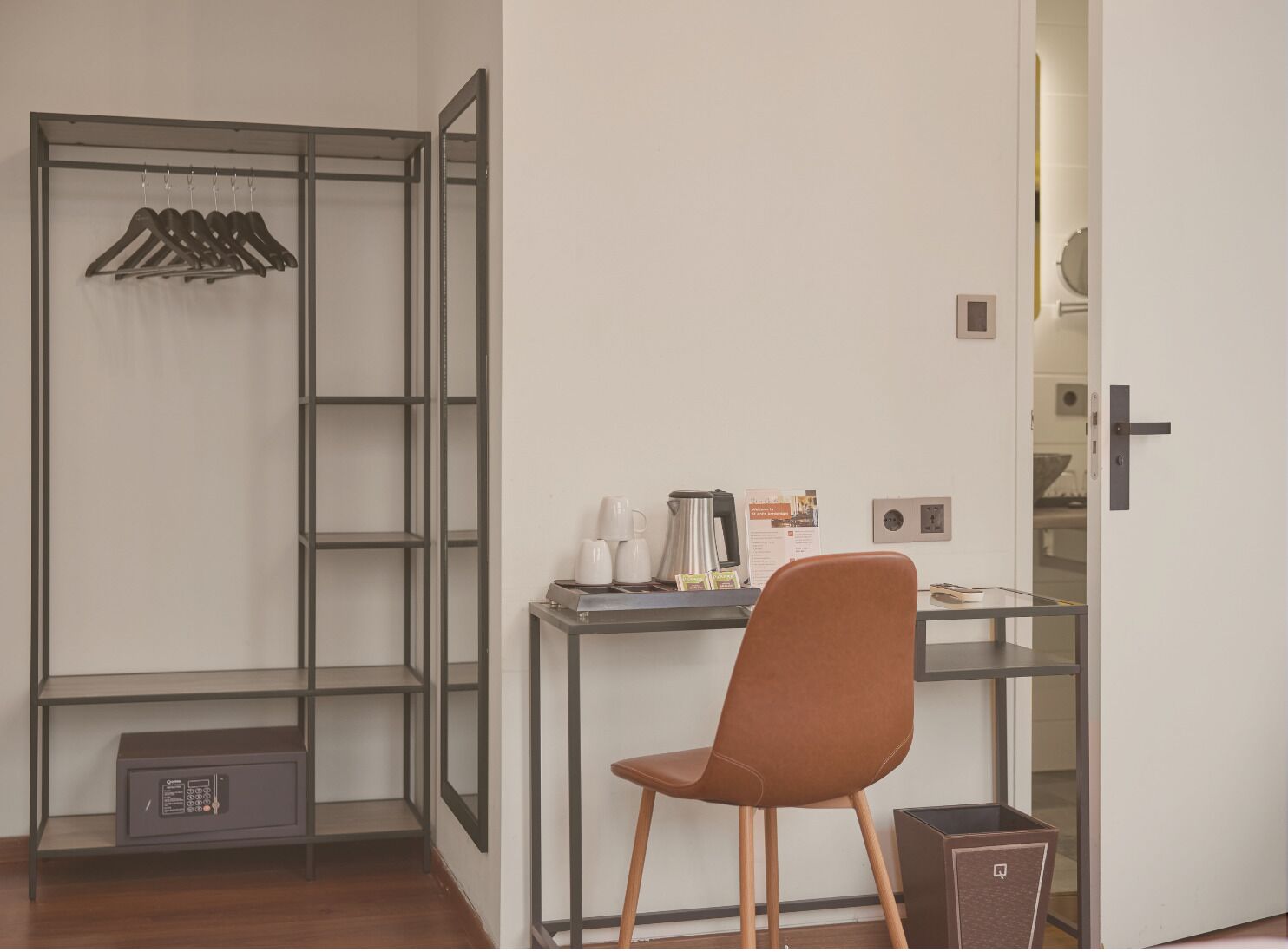 A small, modern room with a desk, chair, and a coat rack.