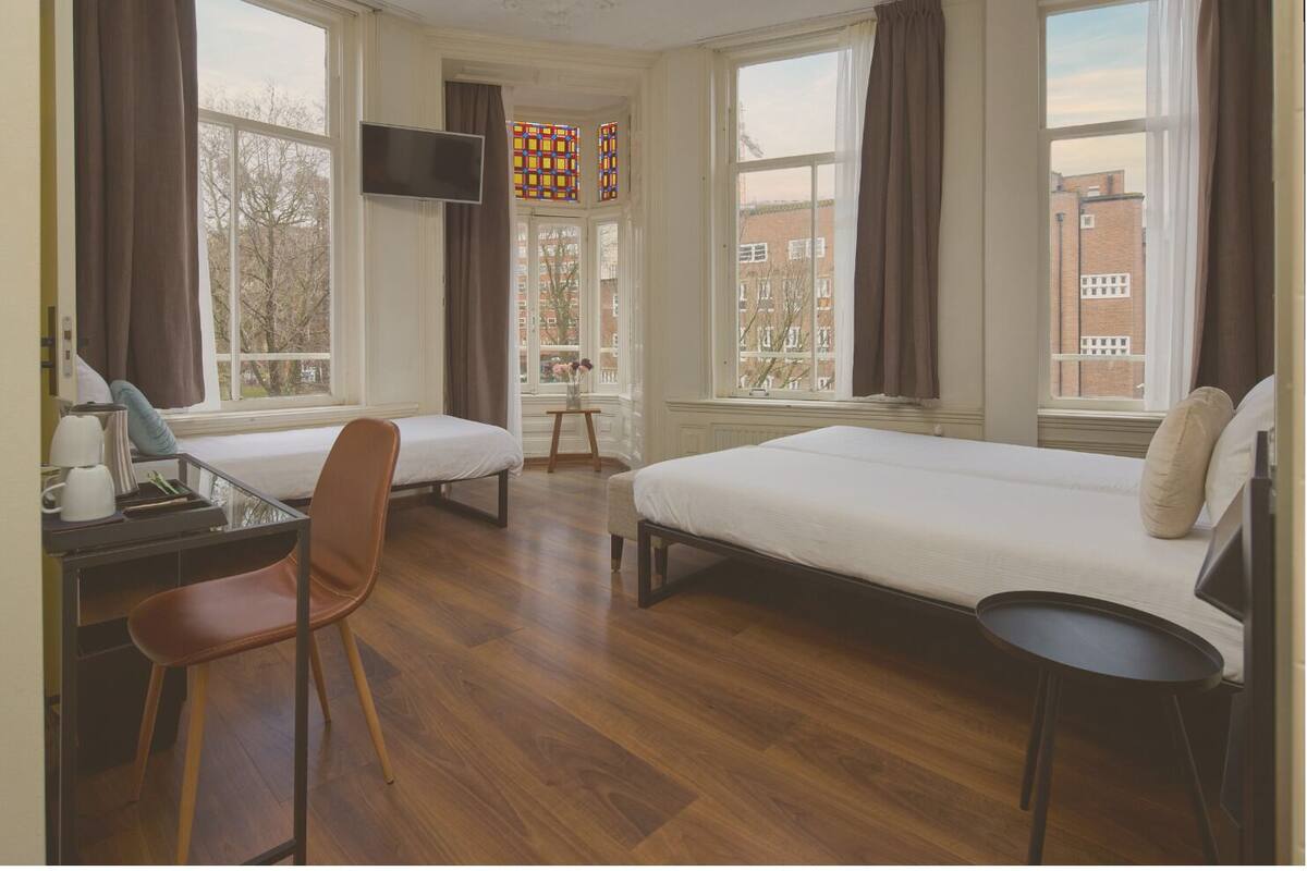 A room with two beds, a desk, a chair, and a TV.