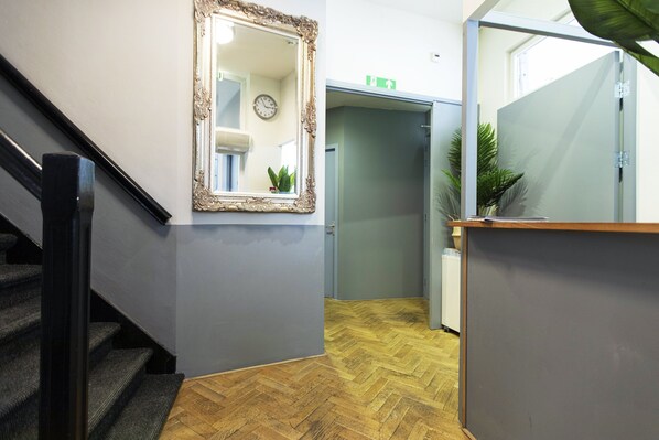 A staircase with a wooden floor and a mirror on the wall.