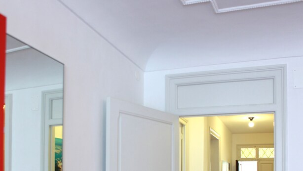 Un pasillo con paredes blancas y una puerta que da a una habitación con ventanal.