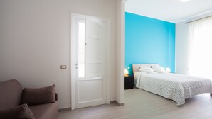 Un dormitorio con cama, mesita de noche y sofá marrón.