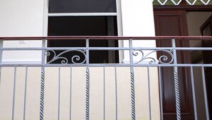 Fachada de edificio con ventana, puerta y barandilla metálica.