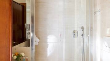 A modern bathroom with a glass-enclosed shower, a white sink, and a toilet.