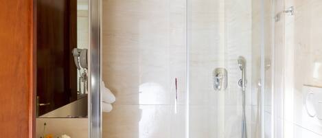 A modern bathroom with a glass-enclosed shower, a white sink, and a toilet.