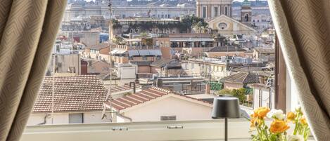 Une pièce comprenant un bureau, une chaise et offrant une vue sur un paysage urbain avec des bâtiments à coupoles.