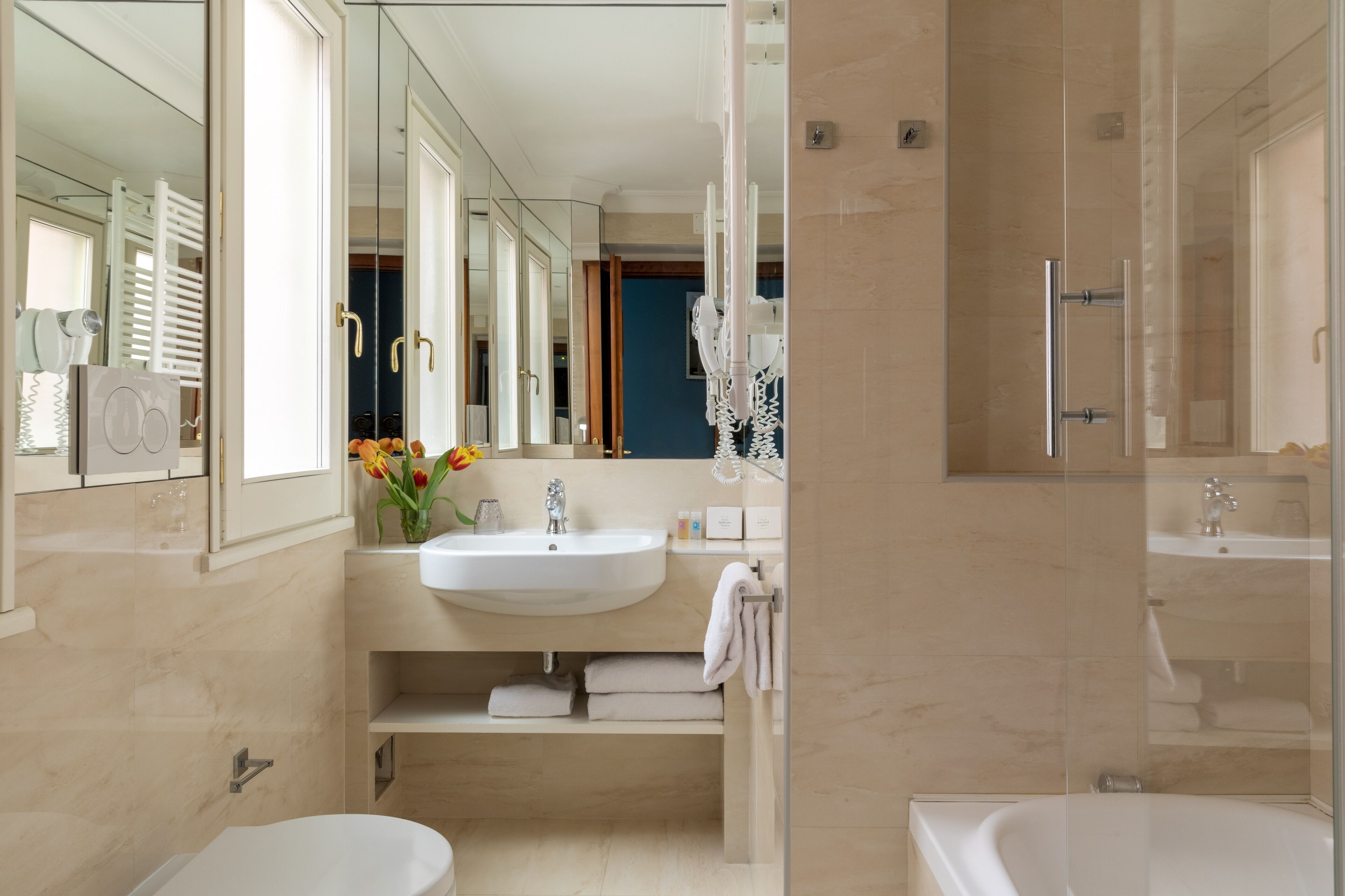 Un baño moderno con un espejo grande, un lavamanos, un inodoro y una bañera.