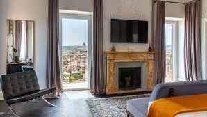 A hotel room with a large window, a fireplace, a flat-screen TV, and a modern sofa. - Hotel Scalinata di Spagna (Rome)