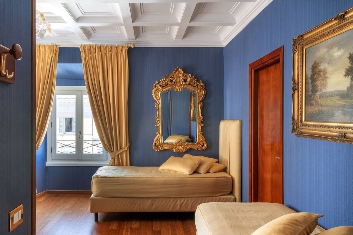 A bedroom with a bed, a large mirror, and a painting on the wall.