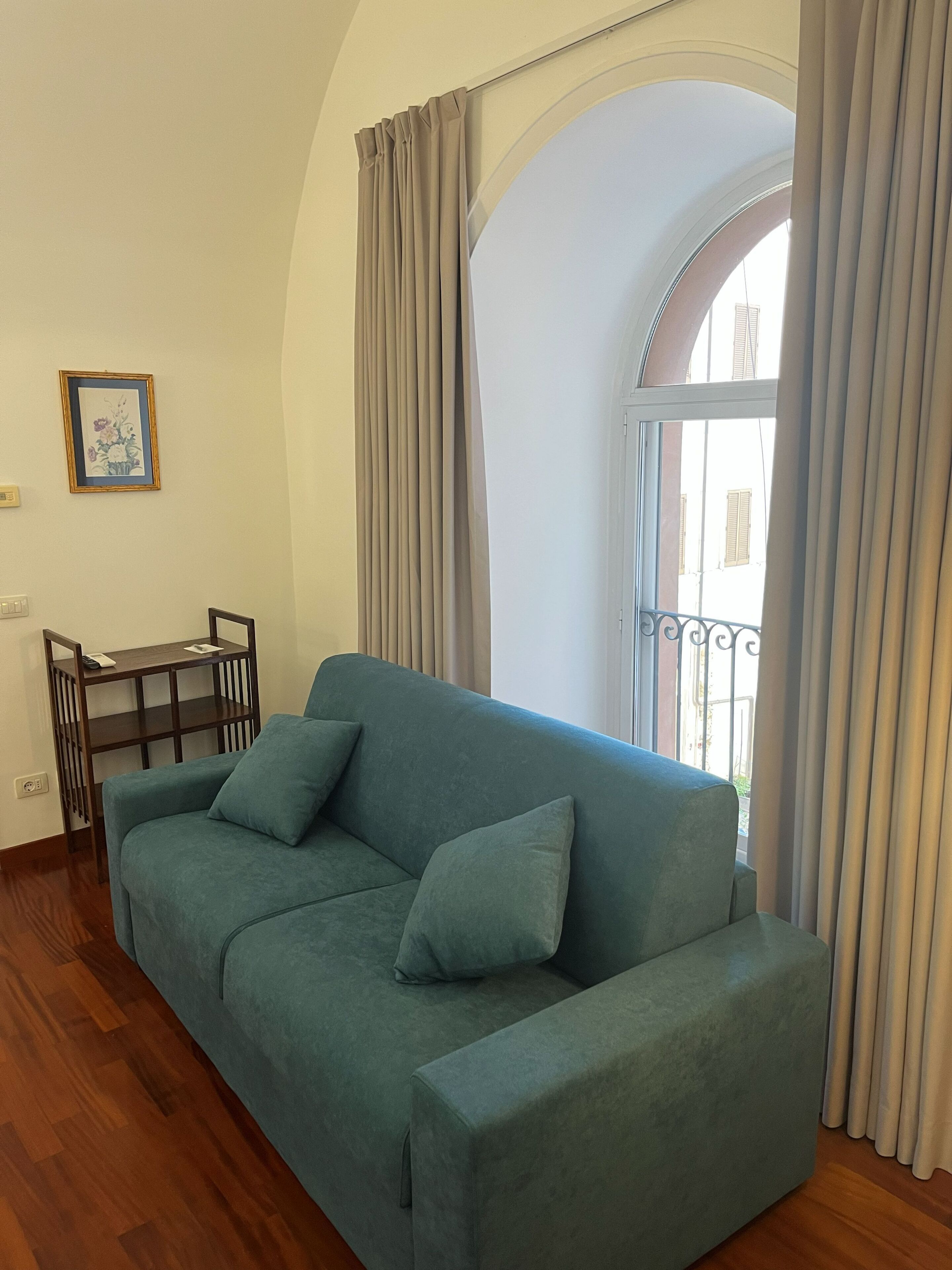 A living room with a sofa, a small table, and a picture on the wall.