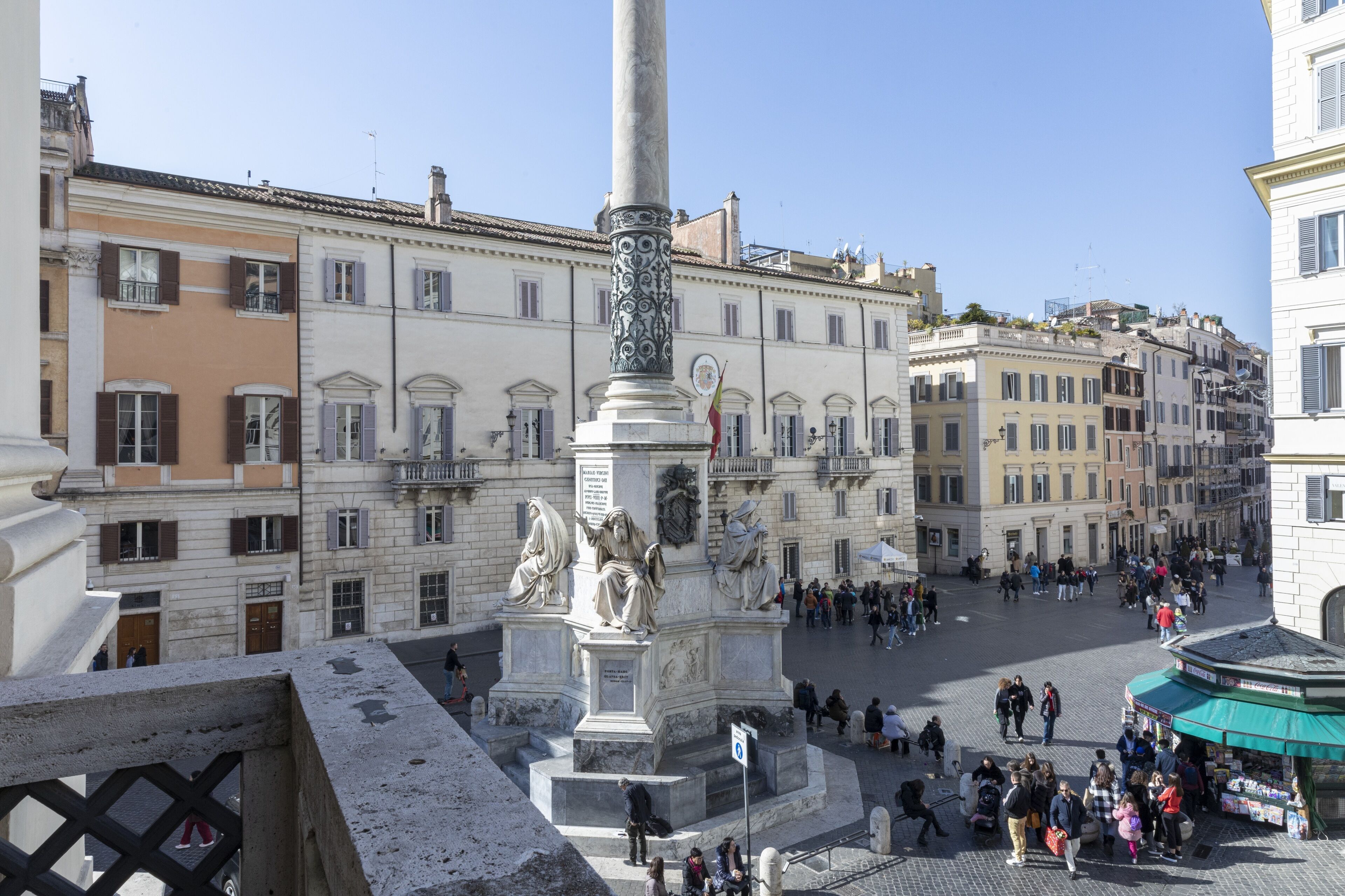 Una plaza pública con un monumento central, rodeada de edificios históricos de arquitectura clásica.