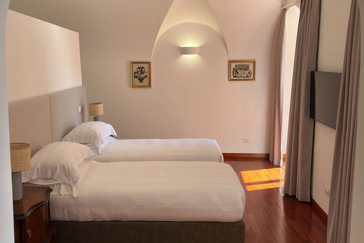 A bedroom with two beds, a TV, and a ceiling light.