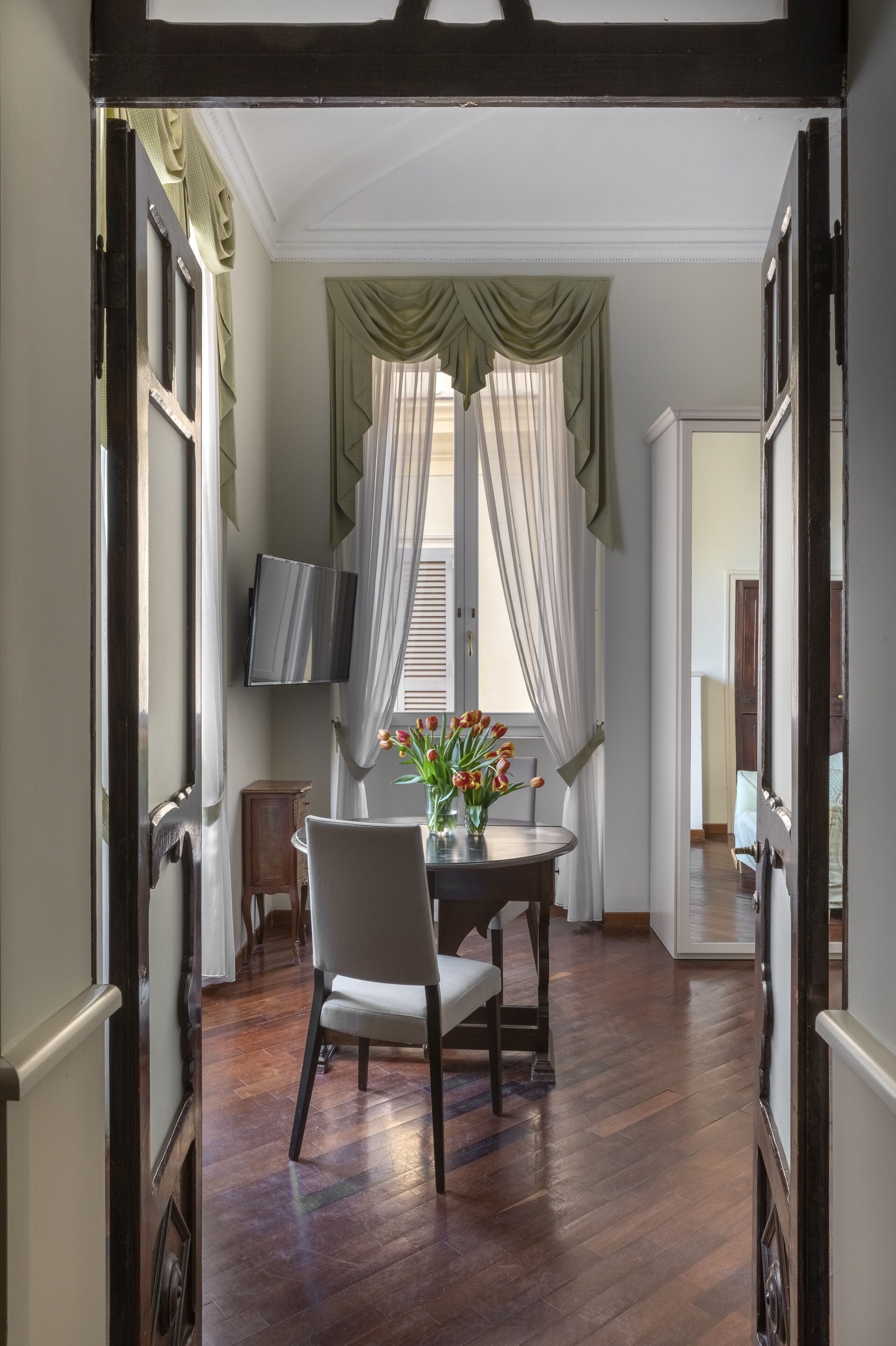 A dining area with a table, chairs, and a vase of flowers.