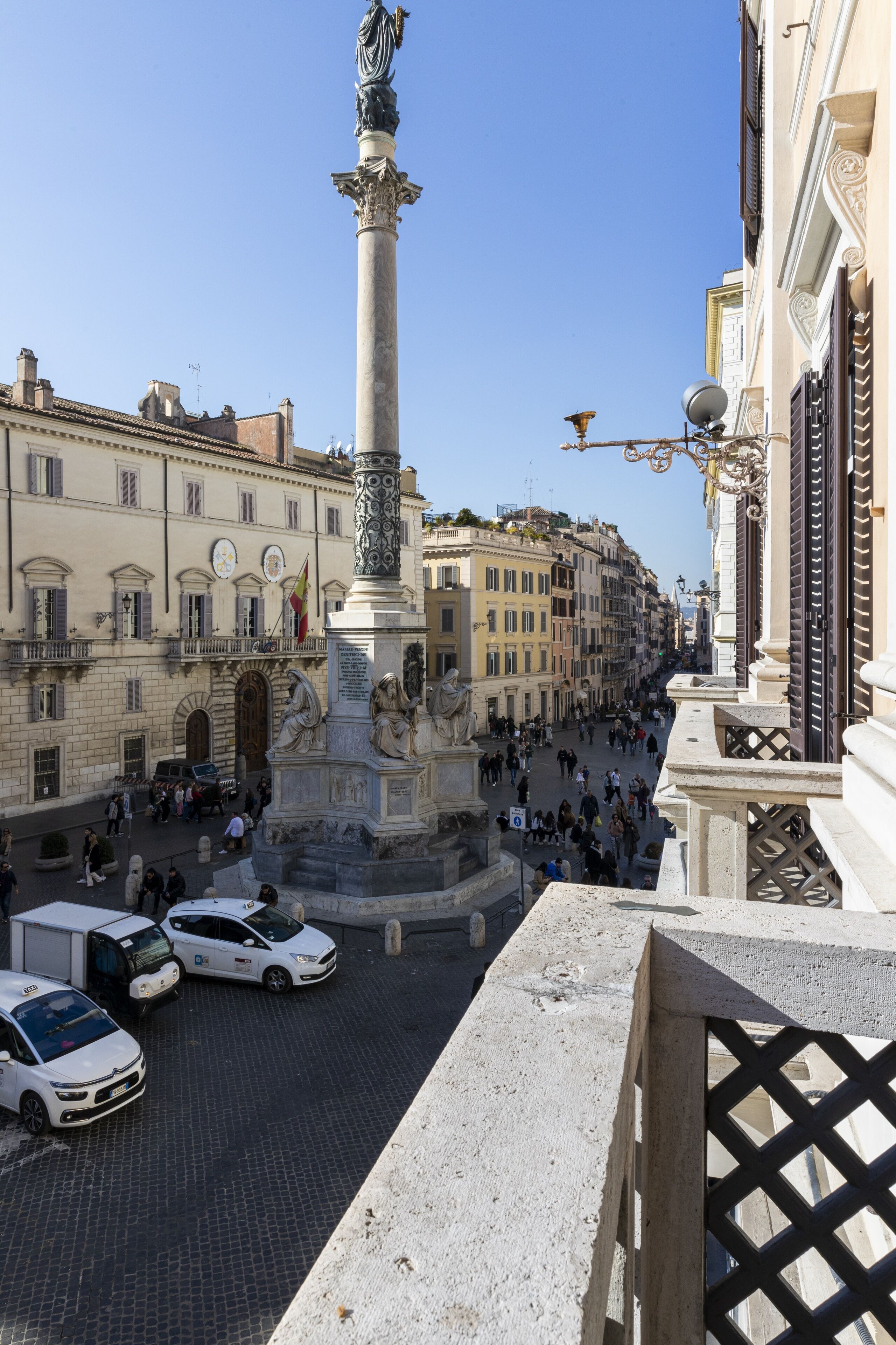 A busy street with a prominent monument, historic buildings, and parked cars.