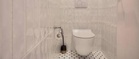 A bathroom with a toilet, a bidet, and a towel rack.