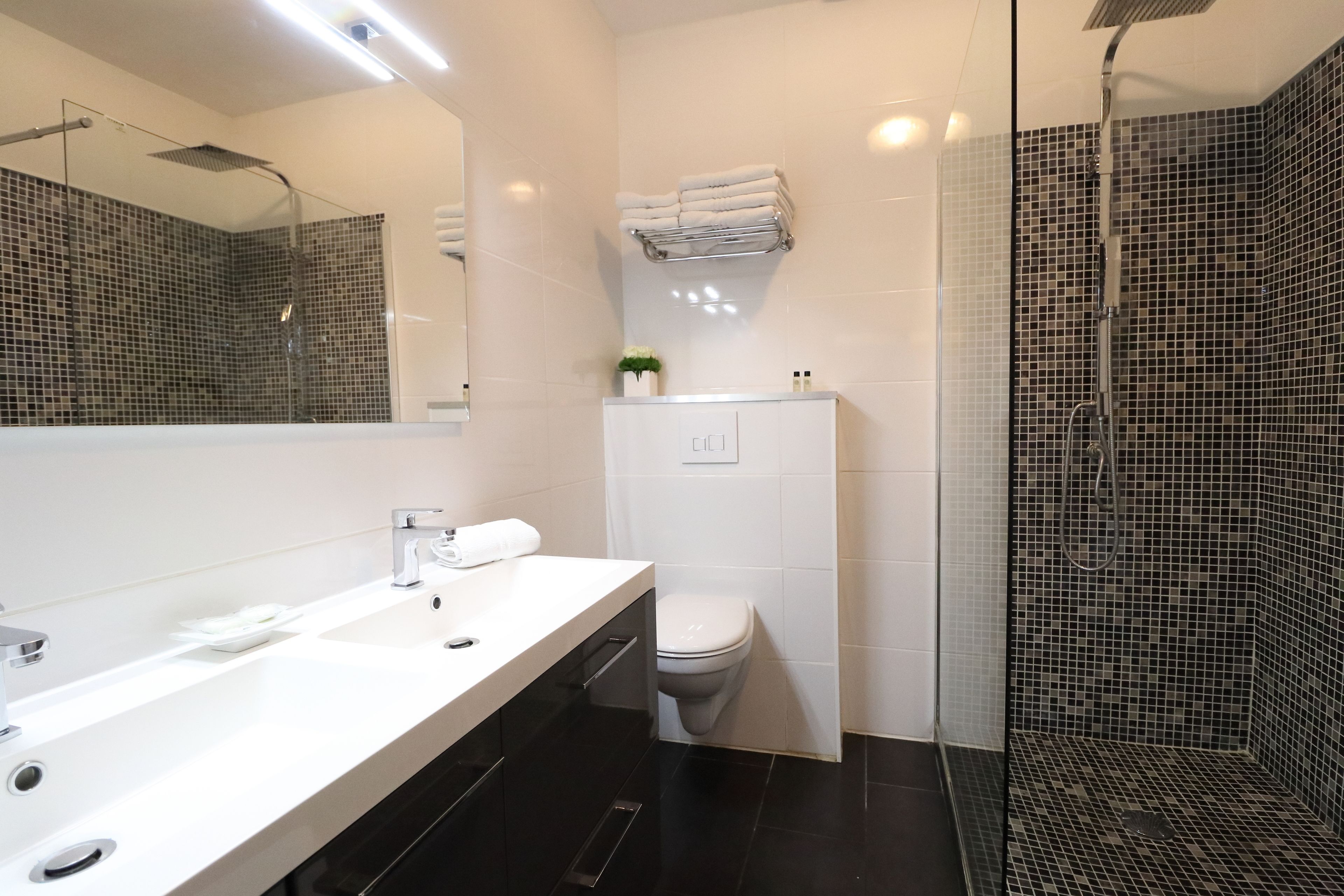 A modern bathroom with a white vanity, a glass shower enclosure, and a tiled floor.