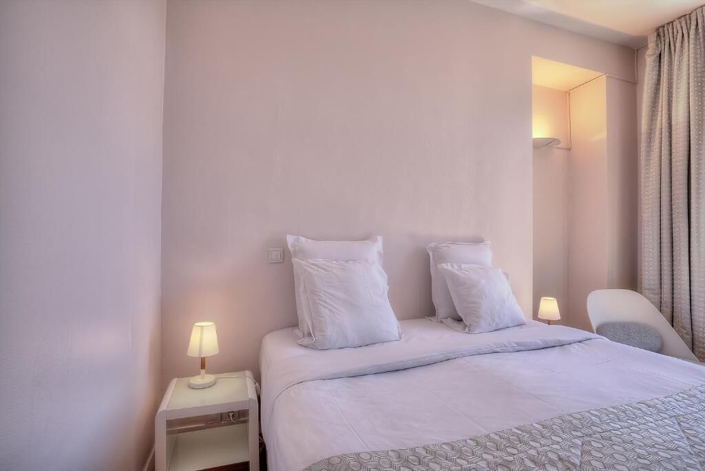 A hotel room with a bed, bedside tables, a chair, and a lamp.