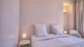 Ein Hotelzimmer mit Bett, Nachttischen, einem Sessel und einer Lampe.