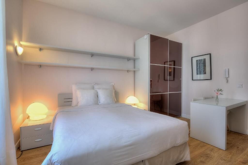 Ein modernes Schlafzimmer mit Bett, Nachttischen, einem Kleiderschrank und einem Schreibtisch.