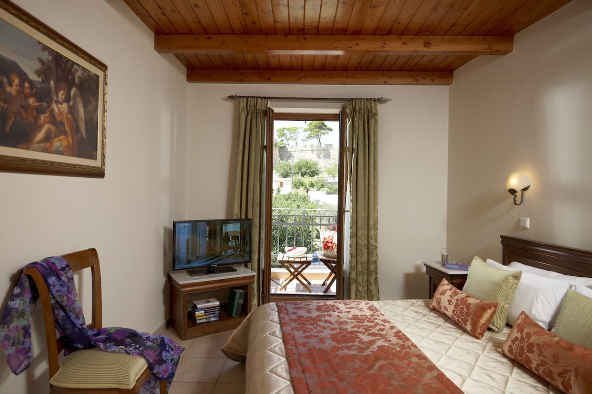 Ein Schlafzimmer mit Holzboden, einem Bett mit floraler Bettwäsche, einem Fernseher auf einem Holztisch und einem Gemälde an der Wand.