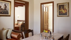 A dining area with a marble table, chairs, and a fruit bowl. There are two paintings on the walls and a wooden ceiling. - Palazzo Vecchio Exclusive Residence (Rethymno)