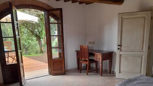 A bedroom with a bed, a desk, and a chair. There is a door and a window. - Tenuta di Seripa (Sassetta)