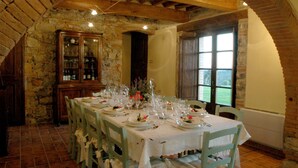 A dining area with a stone wall, wooden ceiling beams, and a large window. - Tenuta di Seripa (Sassetta)