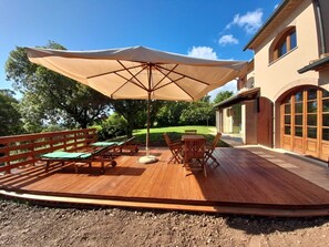 A wooden deck with a large umbrella, lounge chairs, and a table. - Tenuta di Seripa (Sassetta)