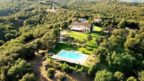 An aerial view of a property with a swimming pool surrounded by lush greenery and a few buildings. - Tenuta di Seripa (Sassetta)