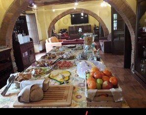 A dining area with a long table set for a meal, featuring various foods and drinks. - Tenuta di Seripa (Sassetta)