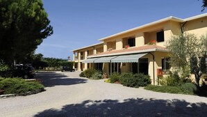 Il s’agit d’un bâtiment à deux étages, doté d’un toit plat et d’un porche avant couvert. On peut voir deux fenêtres à l’étage supérieur et une porte au rez-de-chaussée.