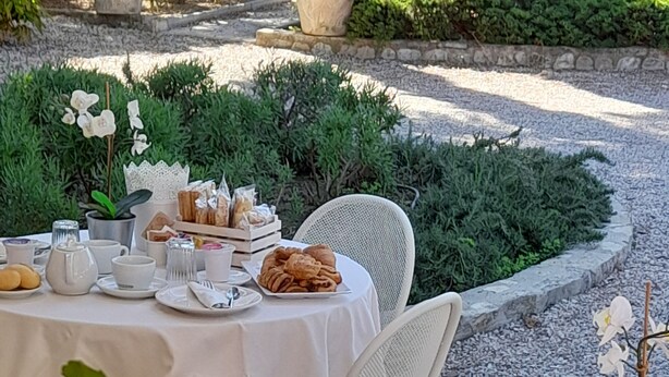 Un espace de restauration en plein air avec des tables rondes, des chaises blanches et une variété de plats et de boissons.