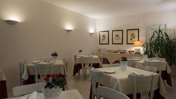 Un espace repas avec des tables dressées pour les repas, un buffet en arrière-plan et des luminaires fixés au mur.