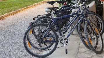 Un vélo équipé d’un panier à l’avant et d’un porte-bagages à l’arrière, garé sur un chemin de gravier.