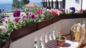 Un balcón con una mesa y sillas, una planta en maceta y vista al mar.