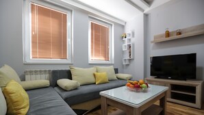 Una sala de estar moderna con un sofá seccional, una mesa de centro de vidrio y un televisor de pantalla plana.