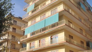 Un edificio de varios pisos con balcones, escaparates y vista a la calle.