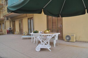 A patio area with a table and chairs, a fan, and a covered seating area. - Hotel Fiorenza (Salerno)