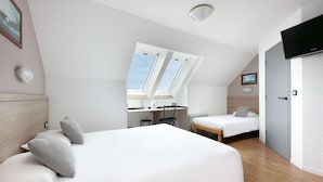 Una habitación de hotel moderna con una cama grande, un escritorio y un televisor.
