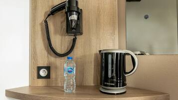 A wooden shelf with a hair dryer, a water bottle, and a black coffee maker.